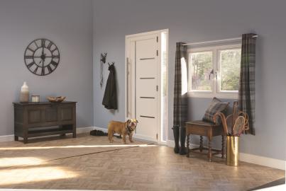 Modern white front door with horizontal metal strips and a long handle, viewed from inside a grey hallway. A bulldog stands on the floor