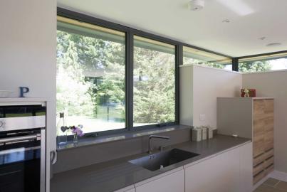 Modern kitchen with a large, dark grey Alitherm casement window over the sink, offering a bright view of a garden