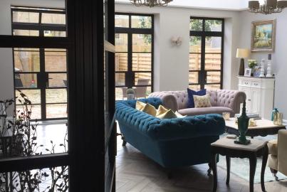 Elegant living room with velvet sofas and a large, black Aluco steel-look door and window system looking onto a patio