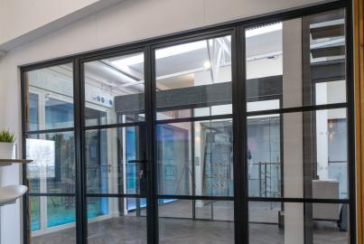 A large, black steel-replacement internal screen and door set with a grid pattern, installed in a modern showroom.