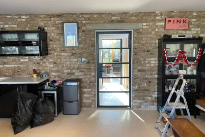 A single black Origin OI-30 internal door with horizontal bars, installed in an exposed brick wall in a kitchen