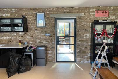 A single black Origin OI-30 internal door with horizontal bars, installed in an exposed brick wall in a kitchen