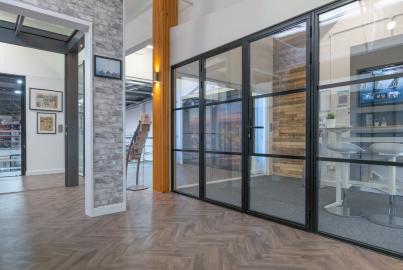Showroom displaying a black steel-replacement french door and screen system with horizontal bars on a herringbone floor
