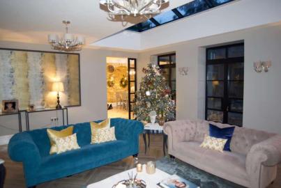 A living room with a Christmas tree, looking towards an internal black steel-look screen and door set leading to another room.