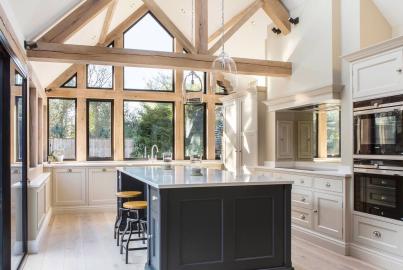 Kitchen with vaulted ceiling and a large wall of black steel-replacement windows, including a triangular apex window