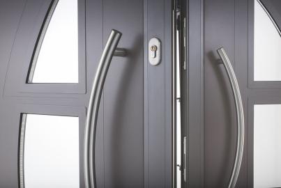 Close-up of grey Origin front double doors, showing the curved stainless steel handles, keyhole, and glass panels
