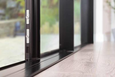 Close-up of a black steel-replacement sliding door, showing the low-profile track on the floor and the locking mechanism