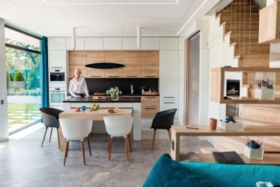 A woman in a modern kitchen with a large Origin OS-77 sliding glass door open to a sunny garden