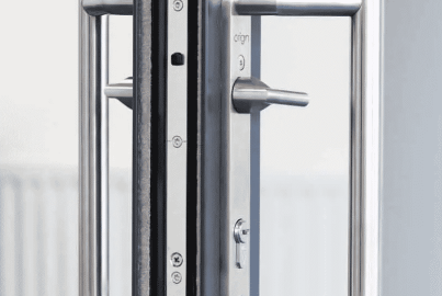 Close-up of the stainless steel D-handle and locking mechanism on a dark grey Origin OS-44 sliding door