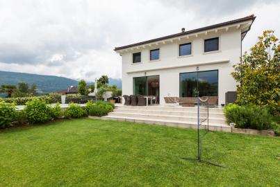 White modern house with a lawn and patio, featuring large Origin sliding glass doors