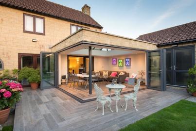 Patio extension with grey Origin bifold doors open to a lit living space, with a second set of doors on the right
