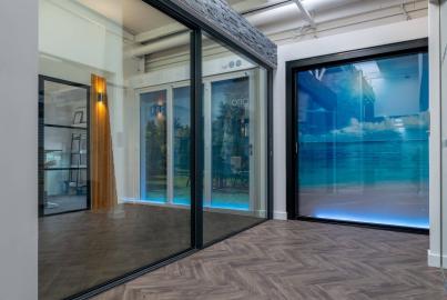 A modern showroom with herringbone floors, displaying large black and white Origin sliding door products