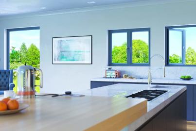 Modern kitchen with a marble island and three grey Origin windows. One casement window is open, showing a green garden