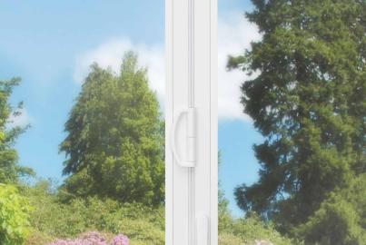 Close-up of a white handle on an Origin OB-49 bifold door, with a sunny garden blurred in the background