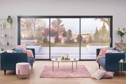 Stylish living room with two armchairs, looking out through a large, black-framed sliding door onto a patio