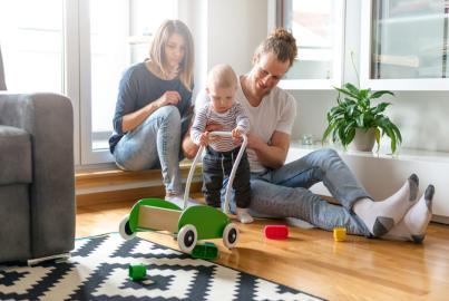 A family plays with a toddler on the floor of a bright living room, near a large Alitherm patio door.