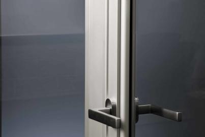 Close-up of a white Alitherm single door, showing the modern dark metal lever handle and locking mechanism