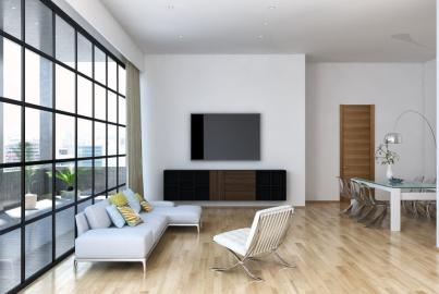 A modern, open-plan living room with a large, black steel-look screen and window wall overlooking a city balcony