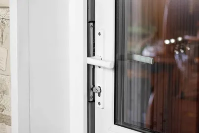Close-up of a white lever handle and keyhole on a white Origin single door, with a reflection in the glass